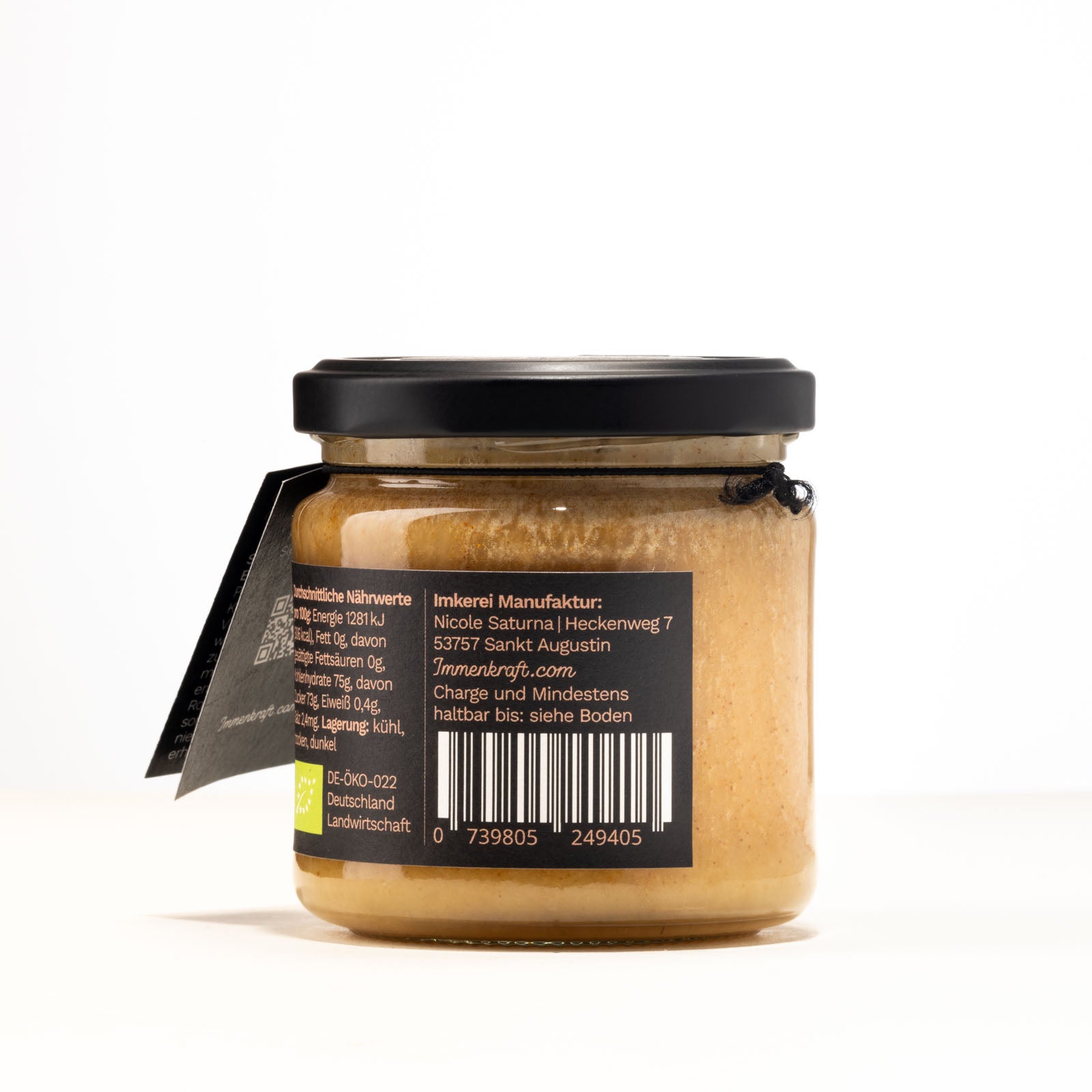Ein 250g klares Twist-Off-Glas mit matt-schwarzem Deckel, schwarzem Anhängeetikett und Etikett mit der Aufschrift Immenkraft - Leben mit der Kraft der Biene. Produktname: Rohpropolis in Honig. Seitenansicht 2: Hersteller und EAN-Code.