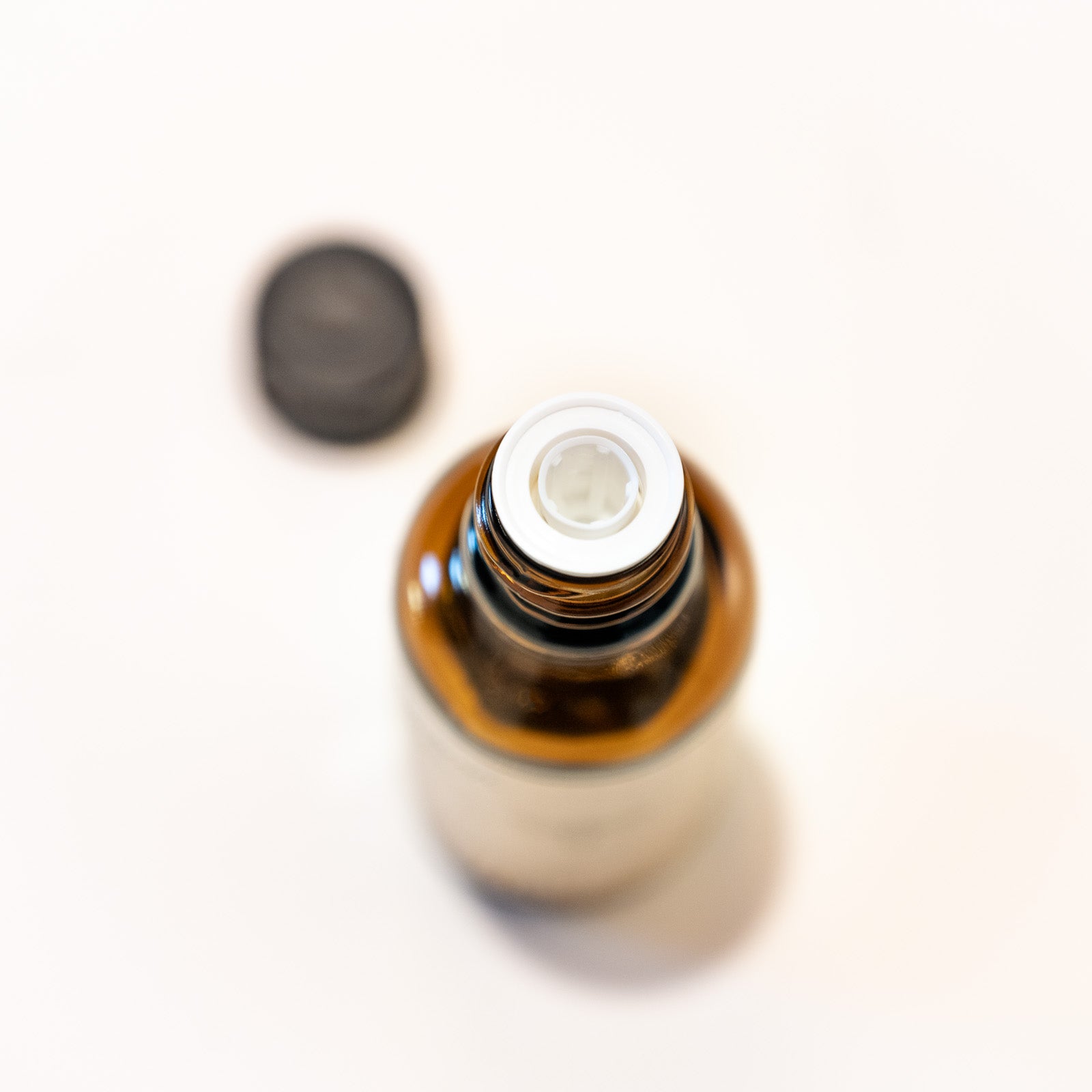 Braunglasflasche mit schwarzem Plastikschraubverschluss und beigem Etikett. Immenkraft, Leben mit der Kraft der Biene. Draufsicht der geöffneten Flasche: man sieht den Tropfverschluss im geöffneten Flaschenhals.
