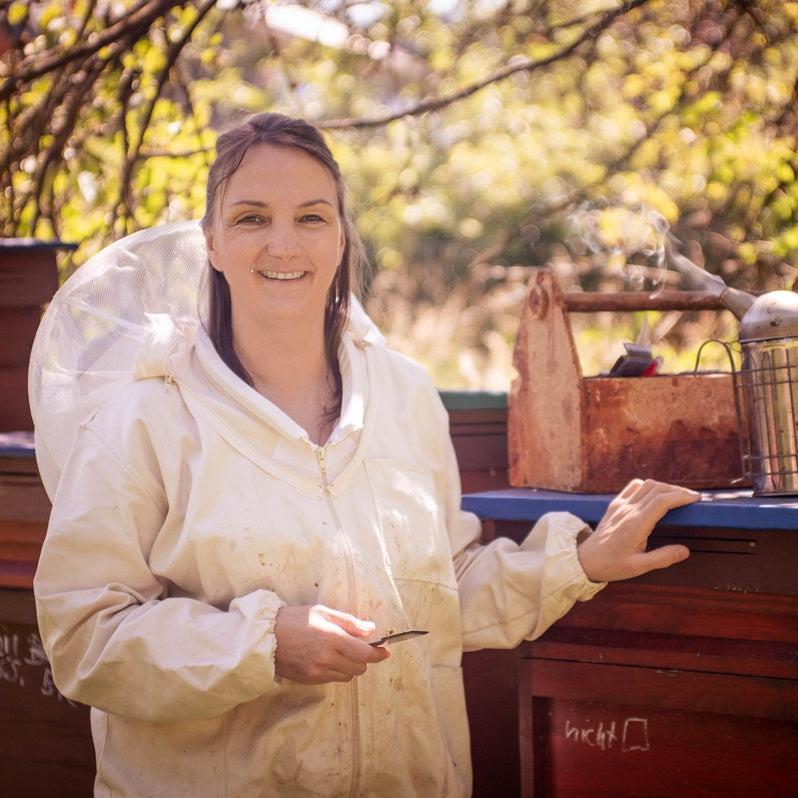 Demeter-Imkerin Nicole Saturna am Bienenstand in Imkerkleidung